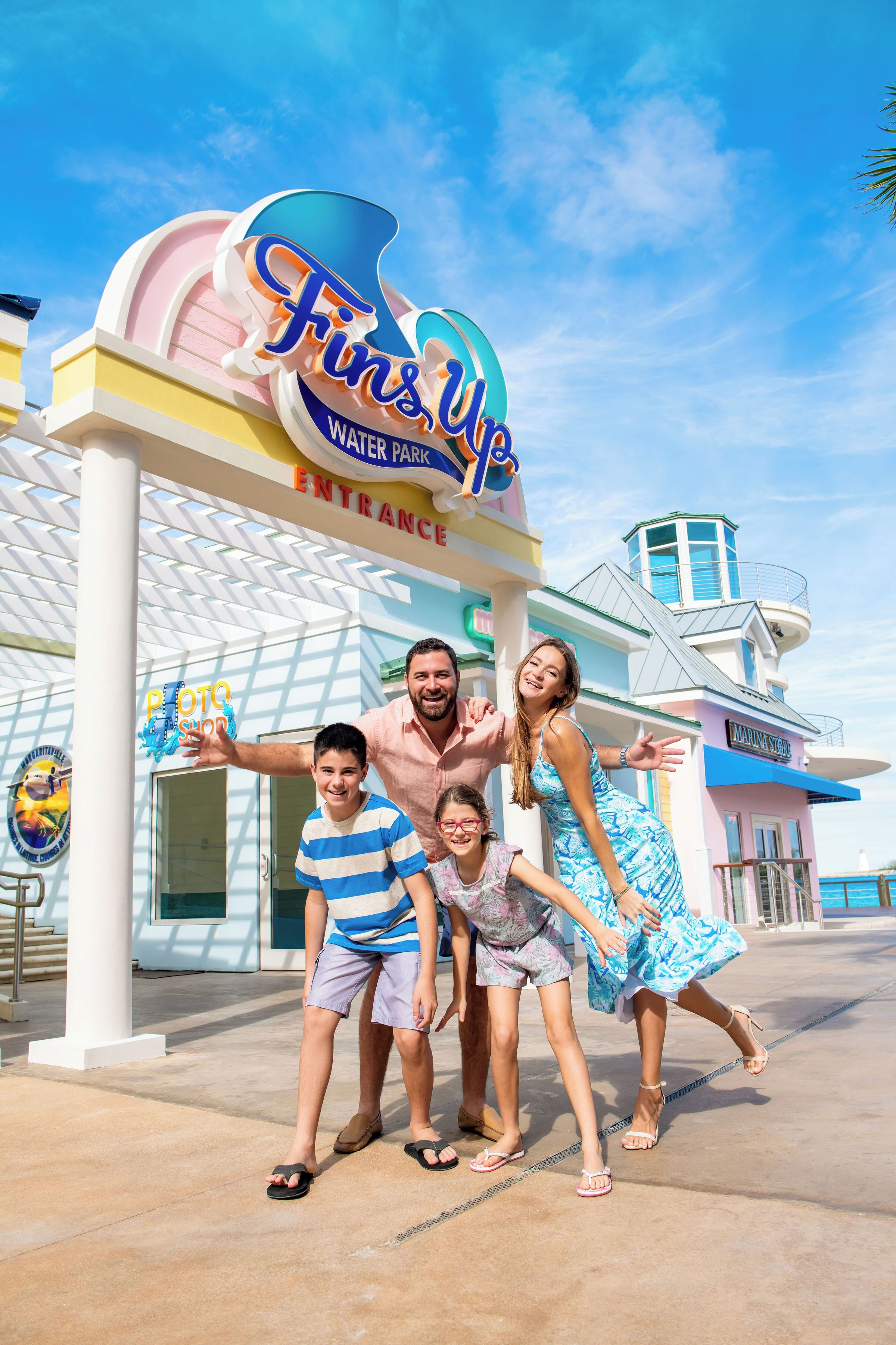 Une famille pose devant une enseigne colorée du parc aquatique Fins Up.