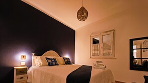 Ein Schlafzimmer mit Bett, Nachttisch, Lampe und einer Hängelampe.
