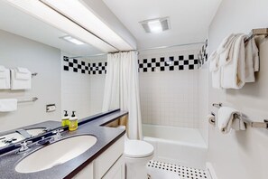 A modern bathroom with a large sink, mirror, toilet, and bathtub. - Bridges 77 at Sugarbush (Warren)