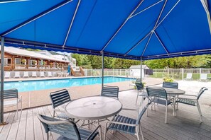 A covered outdoor area with a pool, lounge chairs, and tables. - Bridges 77 at Sugarbush (Warren)