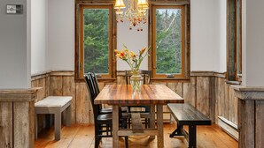 A wooden dining table with chairs, a bench, and a vase with flowers. - Hidden Birch at Sugarbush (Fayston)