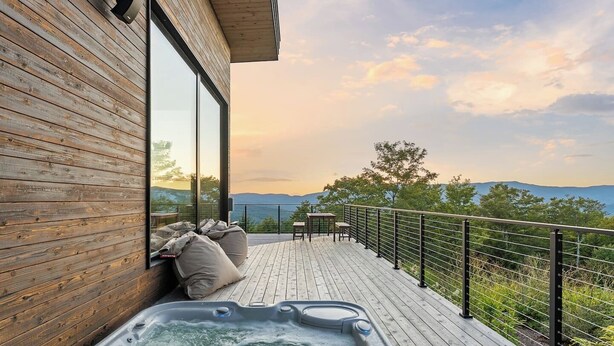 Eine Holzdar Terrasse mit Whirlpool und Sitzgelegenheiten mit Blick auf eine reizvolle Landschaft.