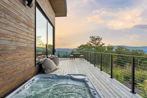 Eine Holzdar Terrasse mit Whirlpool und Sitzgelegenheiten mit Blick auf eine reizvolle Landschaft.