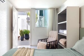 Un dormitorio con cama, una silla, un armario y vistas a una escalera y un espacio exterior.