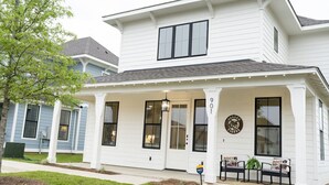 Una casa de dos pisos con un porche, un letrero que dice 'Auburn Tigers' y un buzón.