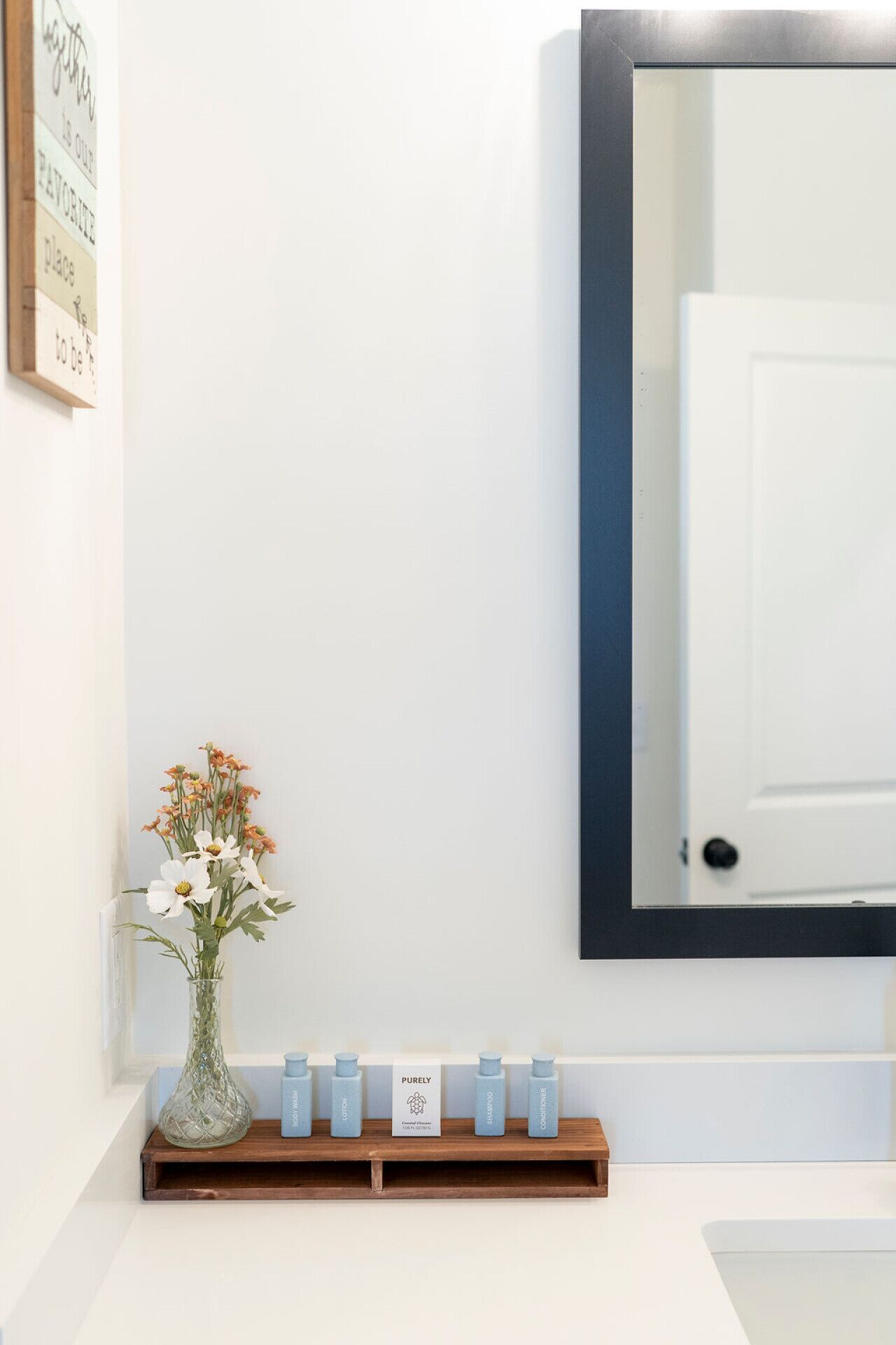 A bathroom with a white sink, a mirror, and a shelf with toiletries.
