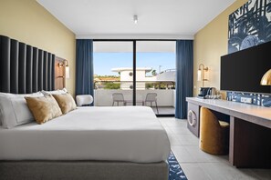 A modern hotel room with a large bed, a desk, and a balcony with chairs. - The Rif at Mangrove Beach Corendon All-inclusive (Willemstad)