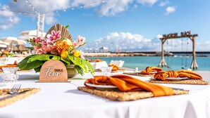 Una mesa dispuesta con un centro de mesa floral, un letrero que dice 'TABLE Four' y vistas al océano y un puente.