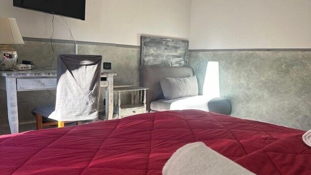 Habitación de hotel con cama, escritorio, silla, televisor y un cuadro en la pared.