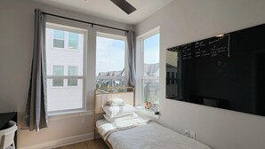 Een kleine, moderne slaapkamer met een enkel bed, een bureau en een prikbord met tekst.