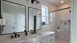 Een moderne badkamer met twee wasbakken, een grote spiegel en een inloopdouche.