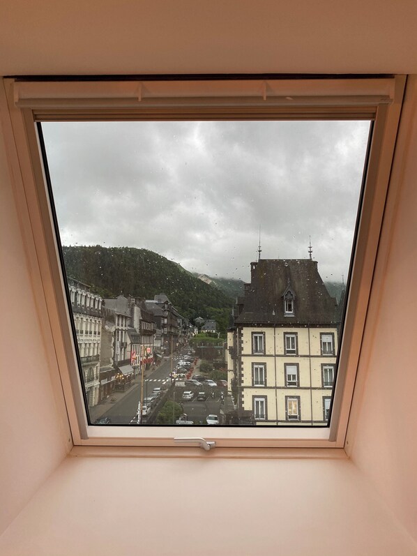 Une vue depuis une fenêtre donnant sur une rue et des immeubles.