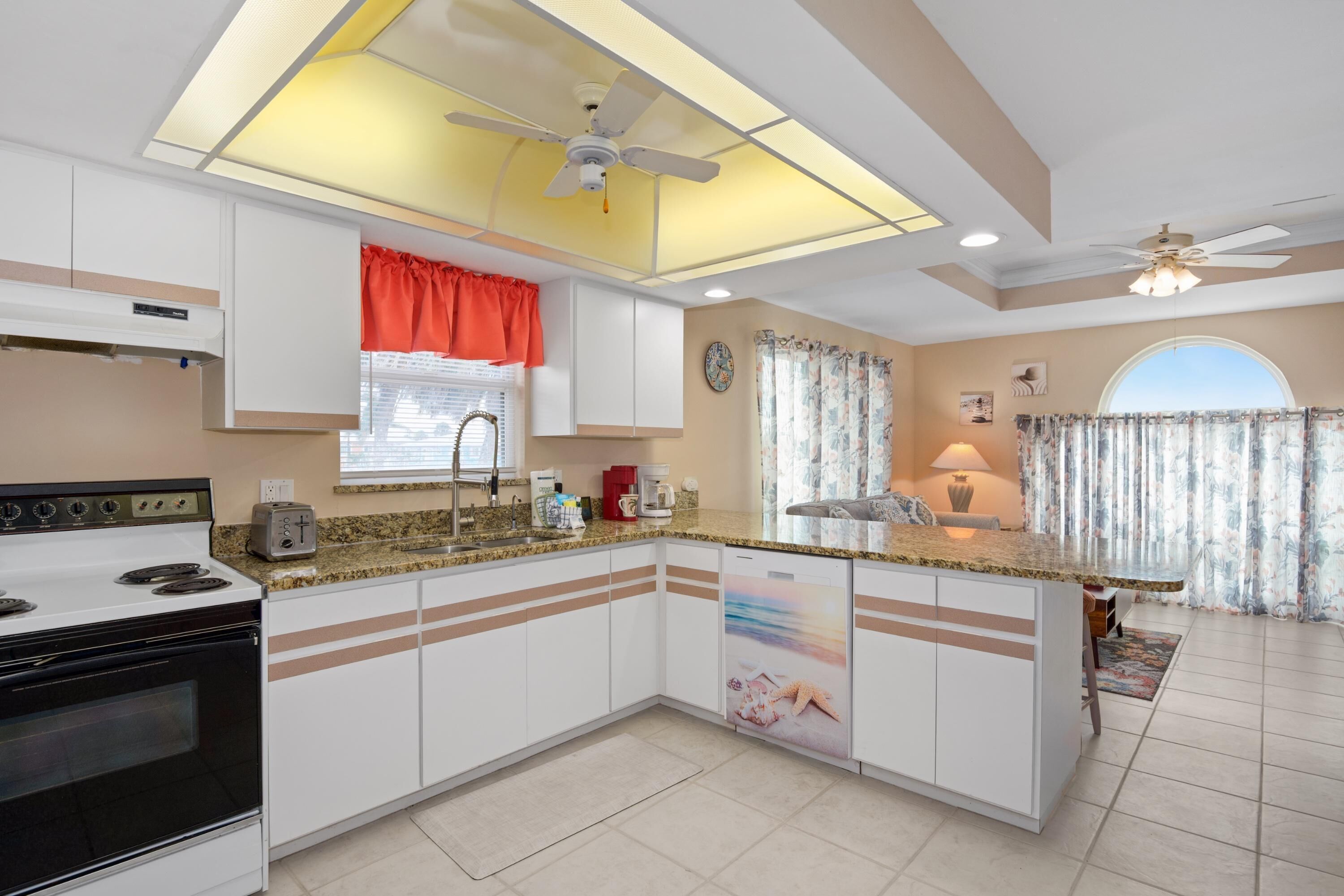 A modern kitchen with a central island, white cabinetry, and a built-in dishwasher.