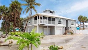 A two-story house with a balcony, a covered porch, and a garage. - Beach Villa (Fort Myers Beach)