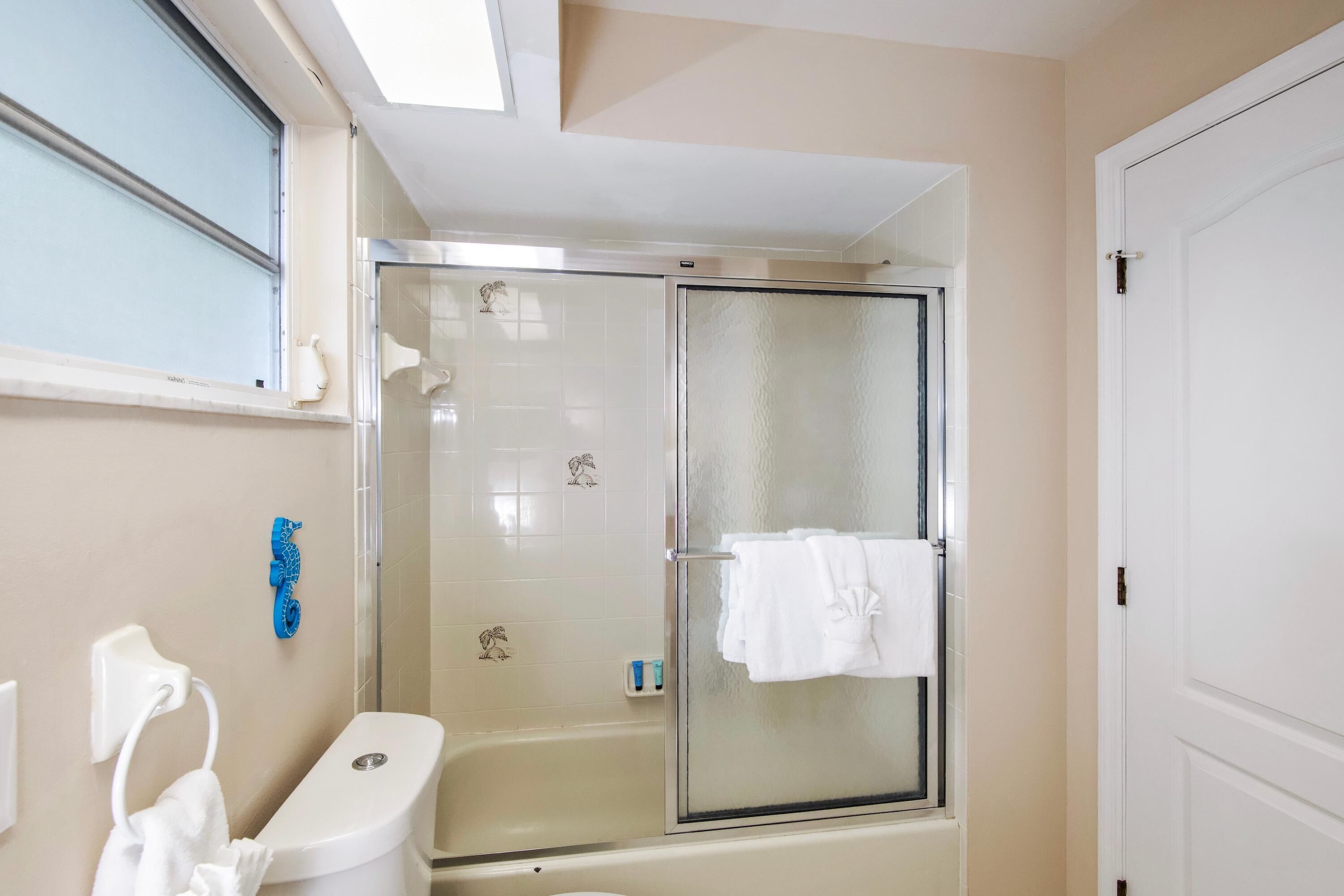 Un baño con inodoro, ducha con mampara de vidrio y bañera.