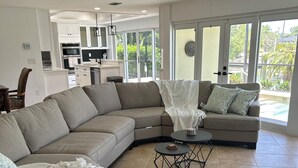 A modern living room with a sectional sofa, a round coffee table, and a ceiling fan. - 3-bedroom house in fantastic Sanibel with AC (Sanibel)