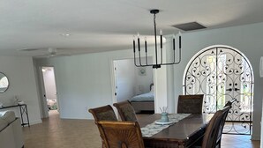 A spacious dining area with a large wooden table and chairs, a chandelier, and a decorative metal gate in the background. - 3-bedroom house in fantastic Sanibel with AC (Sanibel)