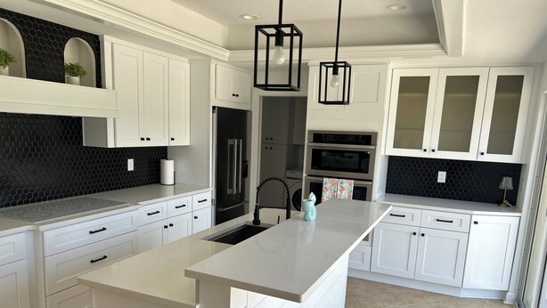 A modern kitchen with white cabinetry, a central island, black appliances, and pendant lighting. - 3-bedroom house in fantastic Sanibel with AC (Sanibel)