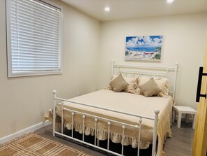 Een keurig opgemaakt slaapkamer met een bed, nachtkastje en een schilderij aan de muur.