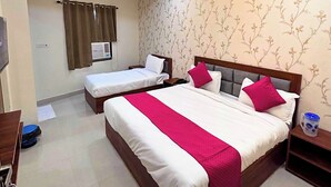 A hotel room with two single beds and a larger bed, all with white bedding and pink accents. - Hotel Om Palace (Vrindavan)