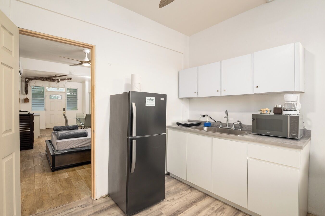 A compact kitchen with white cabinets, a stainless steel refrigerator, a microwave, and a coffee maker.
