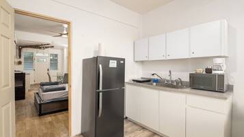 A compact kitchen with white cabinets, a stainless steel refrigerator, a microwave, and a coffee maker.