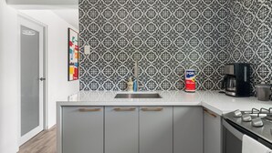 A modern kitchen with a patterned backsplash, a stainless steel sink, and a coffee maker. - RainForest House (Ceiba)