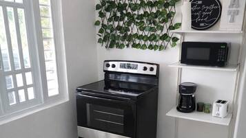 A kitchen with a black stove, a microwave, a coffee maker, and a wall-mounted plant.