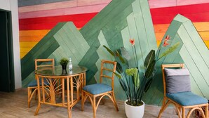 A room with a herringbone-patterned wall, a round glass table, wicker chairs, and a potted plant. - RainForest House (Ceiba)