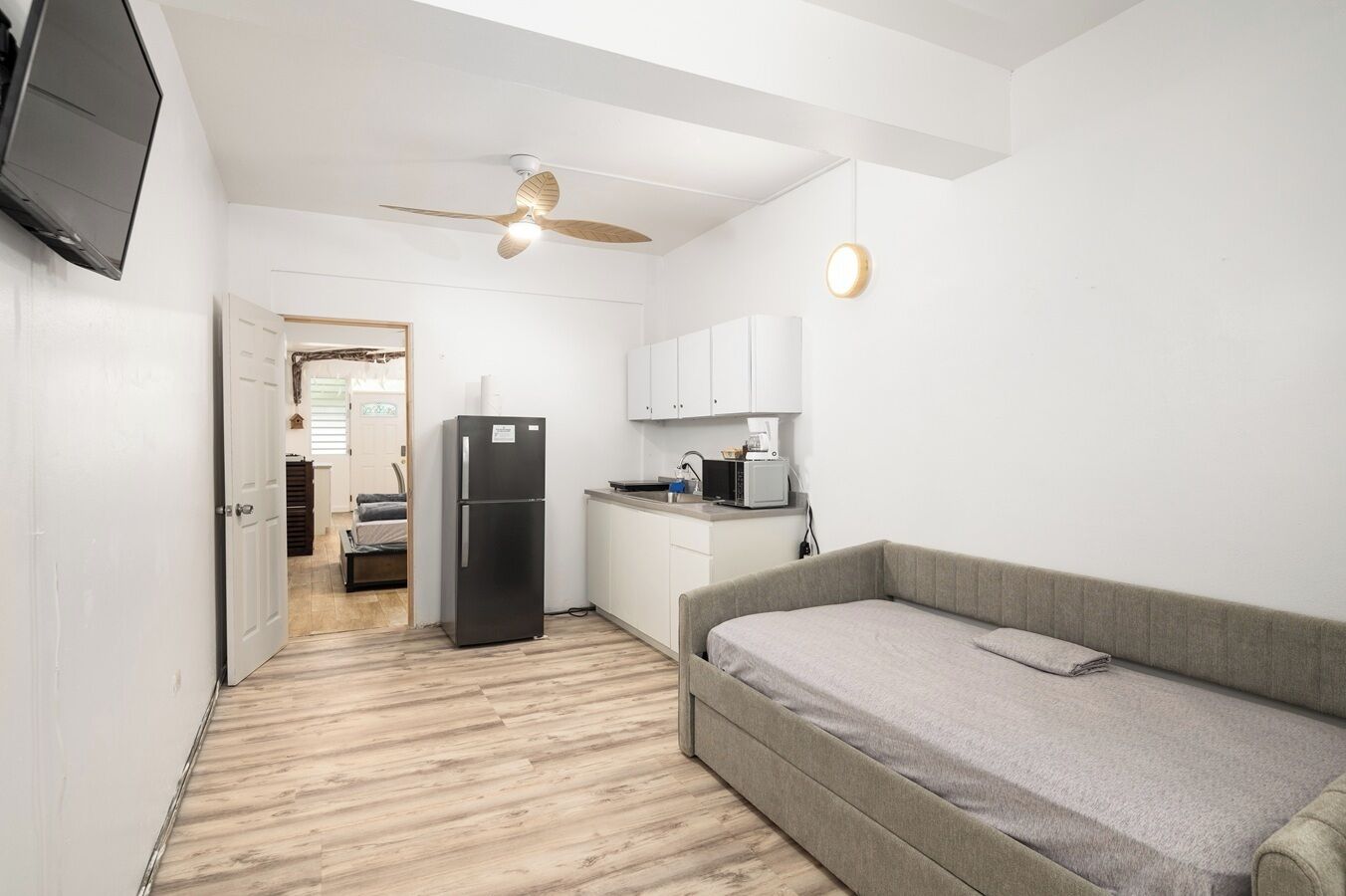 A compact living space with a kitchenette, a bed, and a ceiling fan.