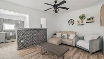 A modern living room with a sofa, a coffee table, and a kitchen area with patterned backsplash.