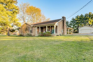 A two-story brick house with a front porch, a garage, and a well-maintained lawn.