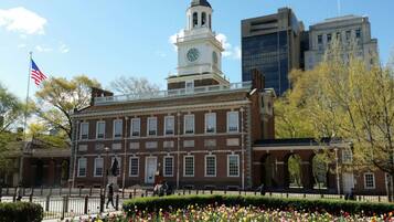 A historic building with a clock tower, surrounded by a garden of tulips and a flag.