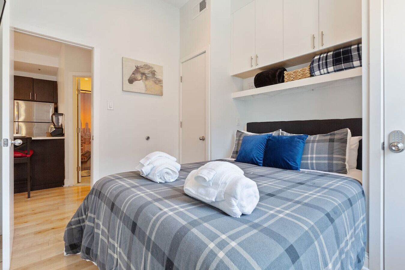 A bedroom with a bed, pillows, a headboard, a wardrobe, and a painting on the wall.