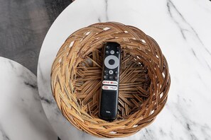 A remote control in a woven basket on a marble surface.