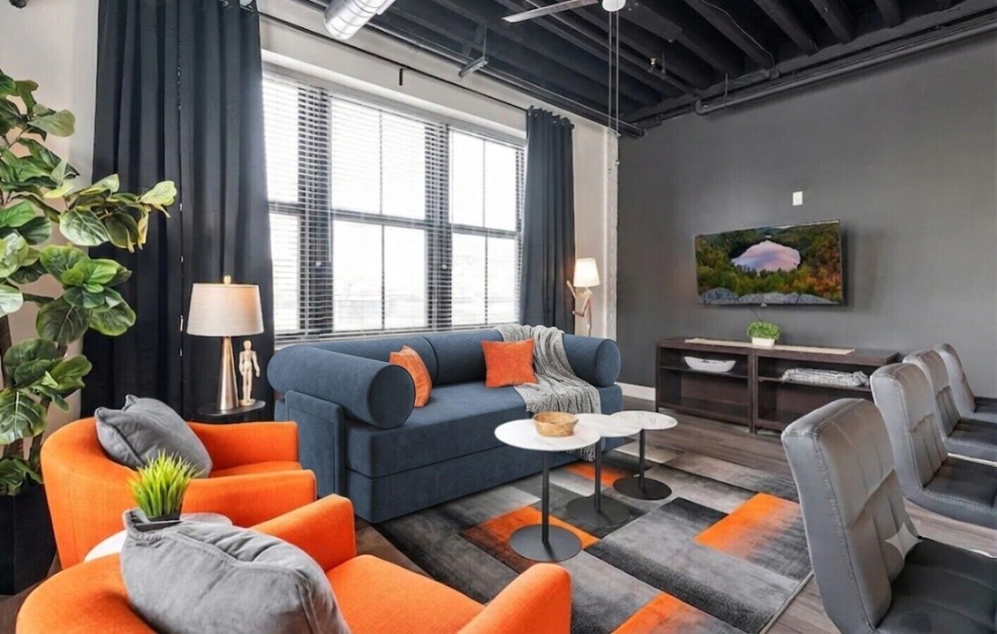 Un salon moderne comprenant un canapé, des fauteuils, une table basse et un téléviseur.