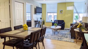 A modern living room with a dining area, featuring a sofa, a coffee table, and a dining table with chairs.