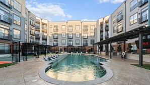 A swimming pool surrounded by a courtyard with a building in the background.