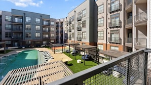 Een modern appartementencomplex met een zwembad op het dak, buitenzitplaatsen en diverse balkons.