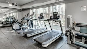 Een sportschool met loopbanden, hometrainers en een roeiapparaat.