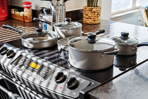 A kitchen with a gas stove, pots, and a spice rack.