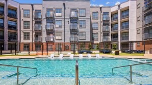 A swimming pool with lounge chairs, surrounded by multi-story buildings with balconies. - Stylish 1Br in Deep Ellum with Free Parking Near Baylor Med (Dallas)