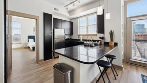 A modern kitchen with a central island, stainless steel appliances, and a large window providing natural light. - Stylish 1Br in Deep Ellum with Free Parking Near Baylor Med (Dallas)