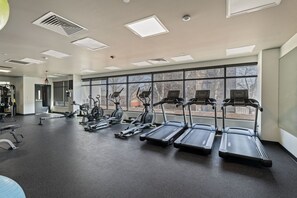 Une salle de sport équipée de tapis de course, de vélos d’appartement et d’un sac de frappe.