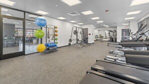 Une salle de sport équipée de matériel d’exercice, notamment des tapis de course, des appareils de musculation et des ballons d’exercice.