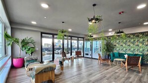 Un hall d’entrée spacieux, doté d’un plancher en bois, de coins salon et de grandes fenêtres offrant une vue sur la ville.