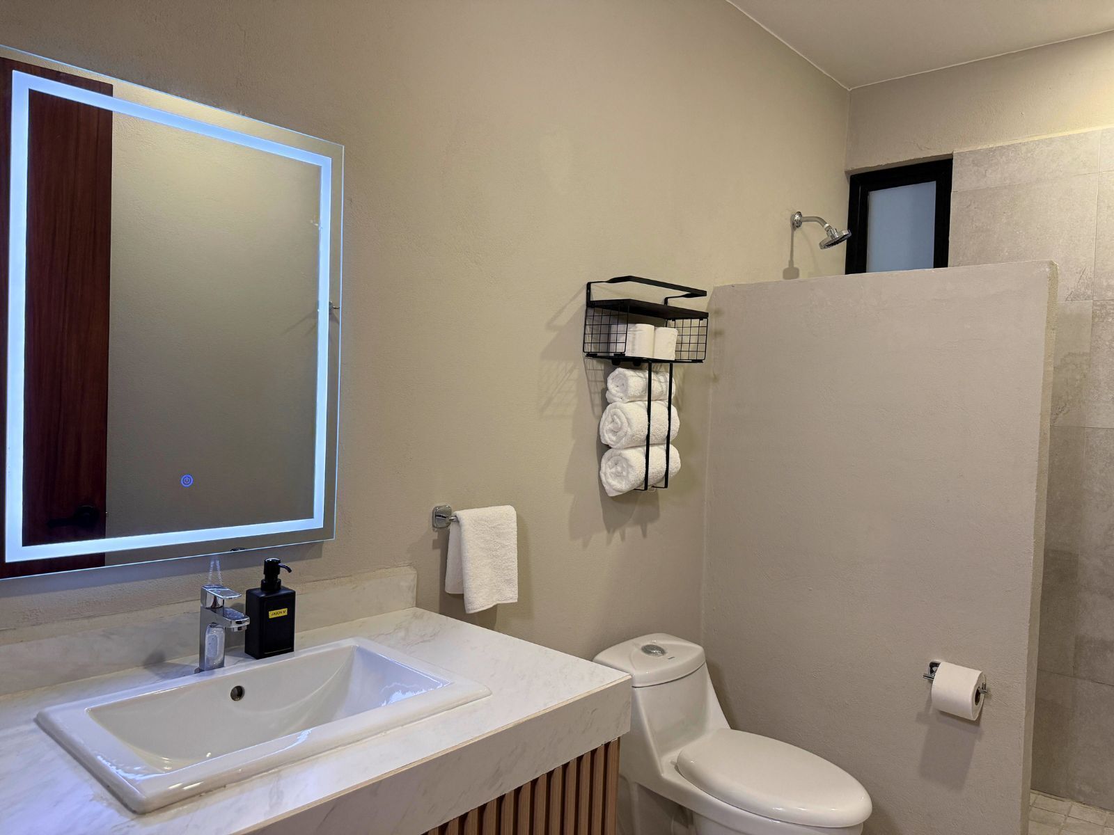 Un baño con lavamanos blanco, espejo, inodoro y zona de ducha.