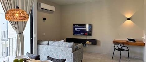 Una sala de estar moderna con un sofá, una mesa de comedor y un televisor montado en la pared.