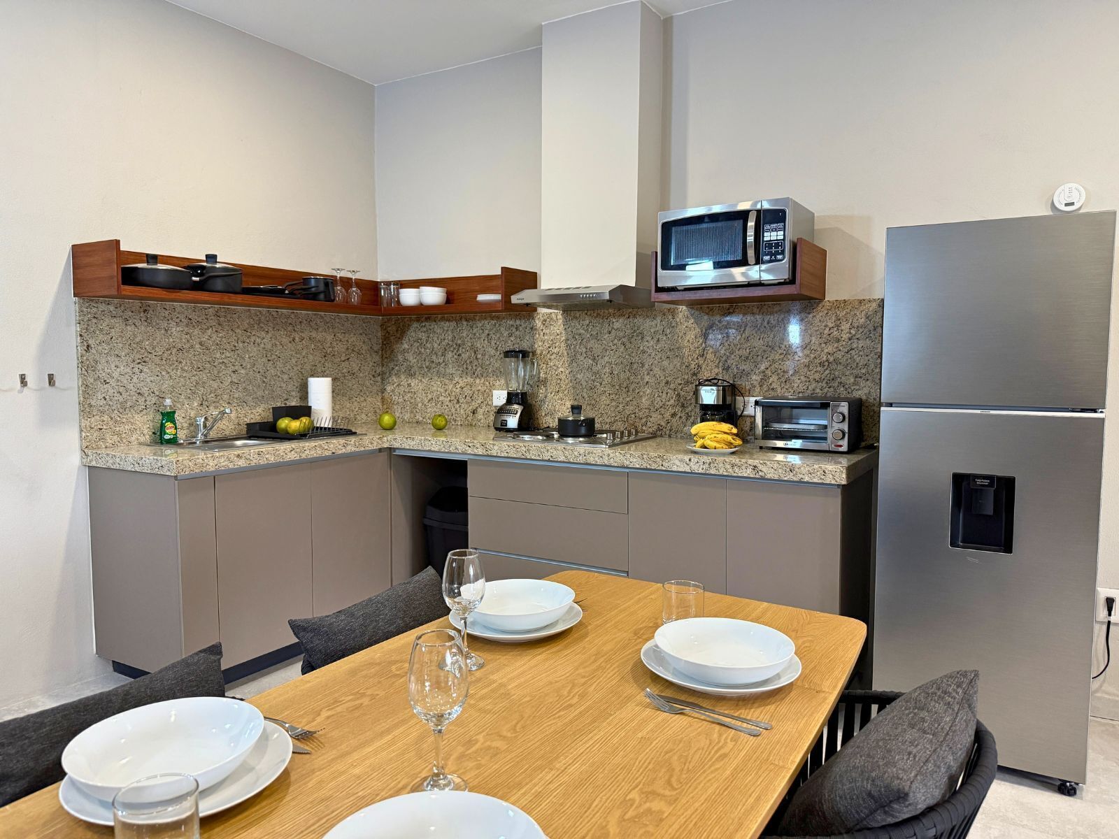 Una cocina moderna con encimeras de granito, microondas, tostadora y refrigerador.