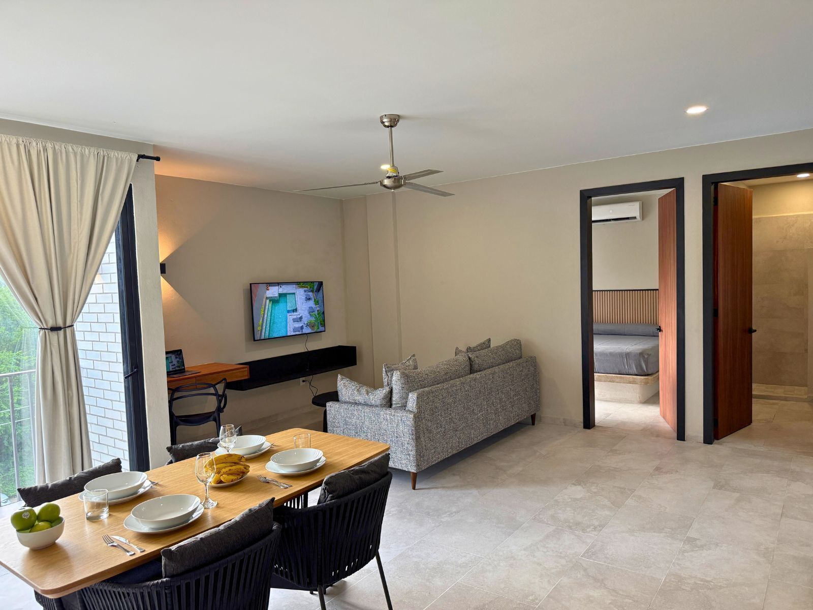 Una sala de estar moderna con comedor, un sofá y un televisor montado en la pared.